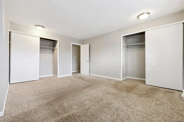 a view of an empty room with closet and a bathroom