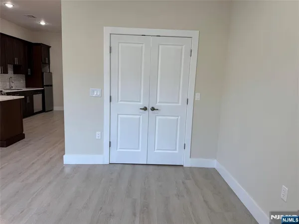 an empty room with wooden floor and kitchen view