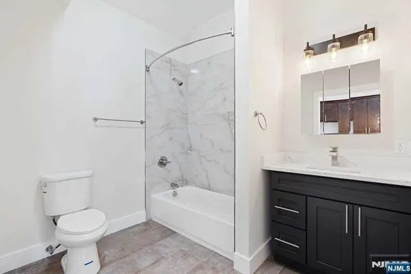 a bathroom with a toilet a sink a mirror a bathtub and vanity