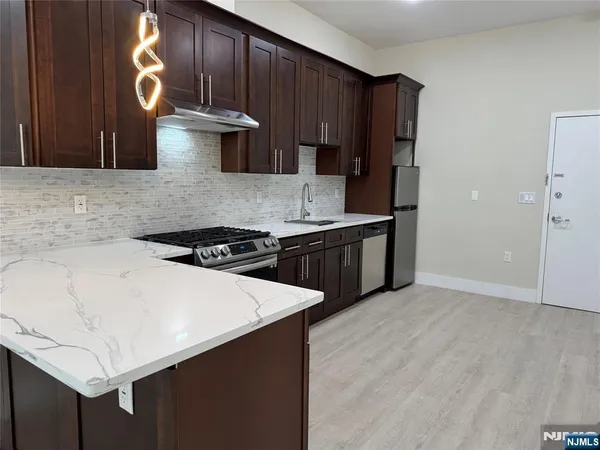 a kitchen with stainless steel appliances a stove a sink cabinets and wooden floor