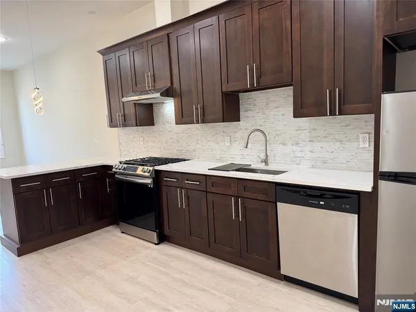 a kitchen with granite countertop a refrigerator stove and sink