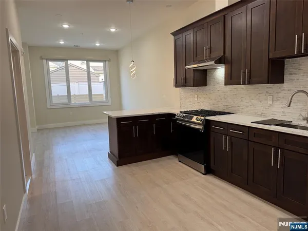 a kitchen with stainless steel appliances granite countertop a sink a stove a refrigerator cabinets and wooden floor