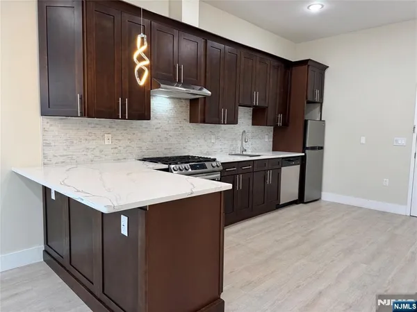 a kitchen with stainless steel appliances granite countertop a stove a refrigerator and a sink with wooden cabinets