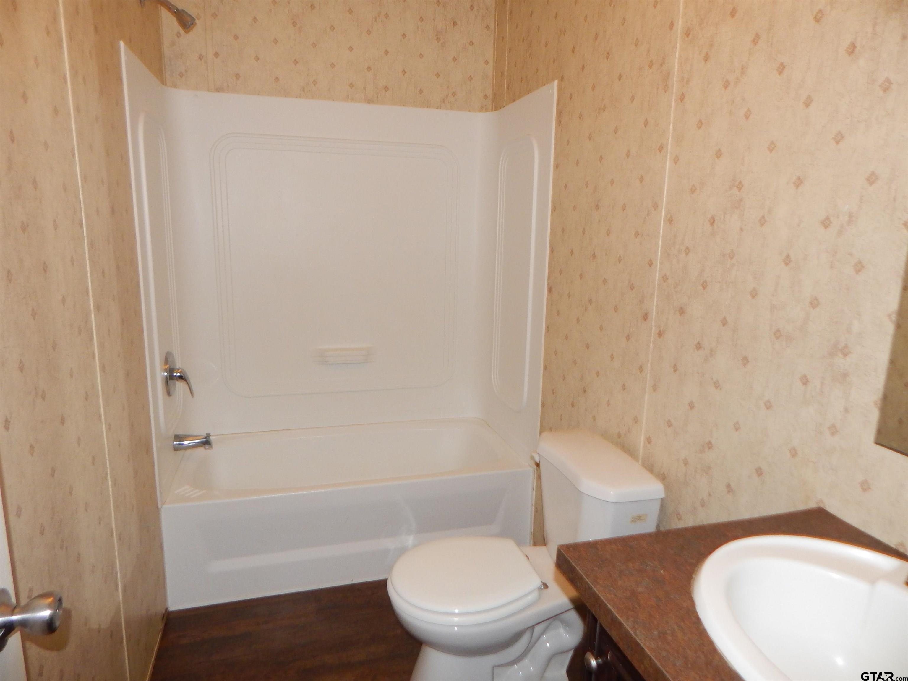 958 Boles Road Gilmer, TX 75645 - Photo 18 of 29 a white toilet sitting next to a bath tub