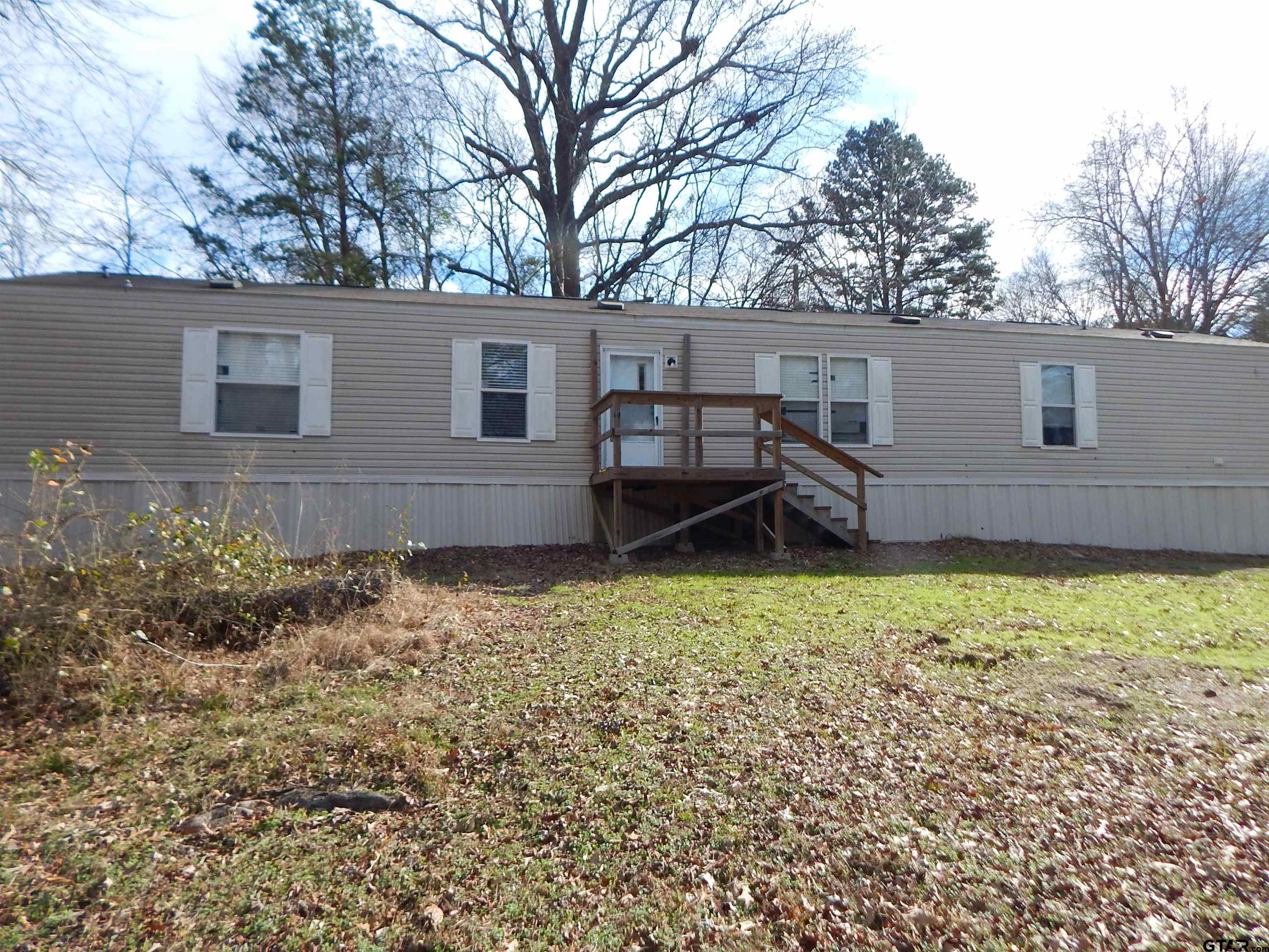 958 Boles Road Gilmer, TX 75645 - Photo 27 of 29 a backyard of a house with wooden fence and large trees