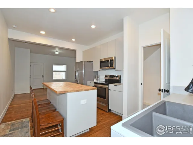 a living room with stainless steel appliances kitchen island granite countertop a sink and a refrigerator