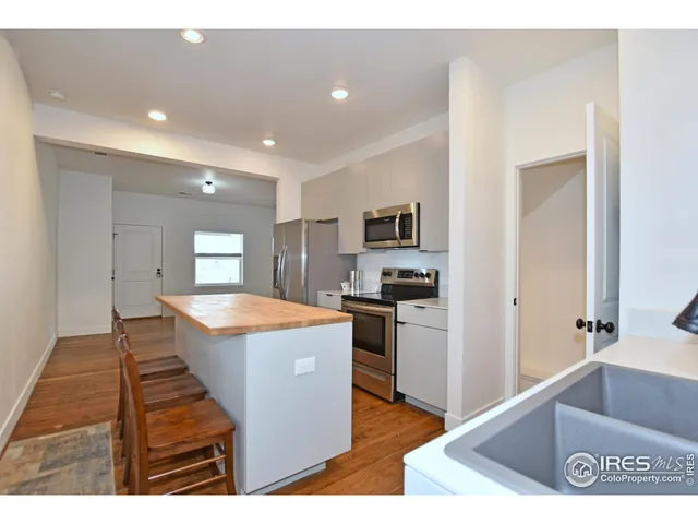 a view of a kitchen with kitchen island a sink a counter top space and stainless steel appliances