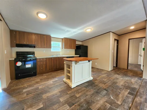 a kitchen with a refrigerator a microwave oven and a sink with wooden floor