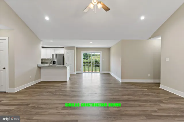 a view of an empty room with kitchen and a window