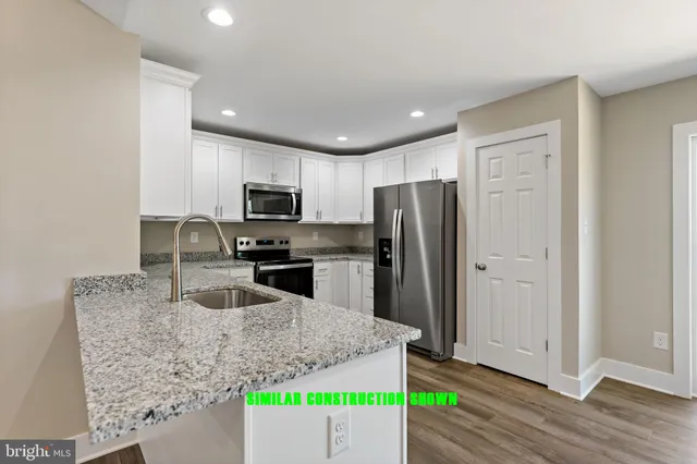 a kitchen with granite countertop a refrigerator and a sink