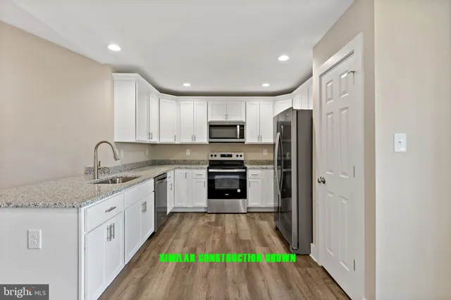 a kitchen with granite countertop a sink stainless steel appliances and white cabinets