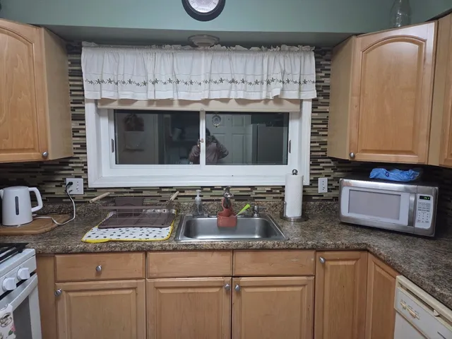a kitchen with granite countertop a sink a stove and cabinets