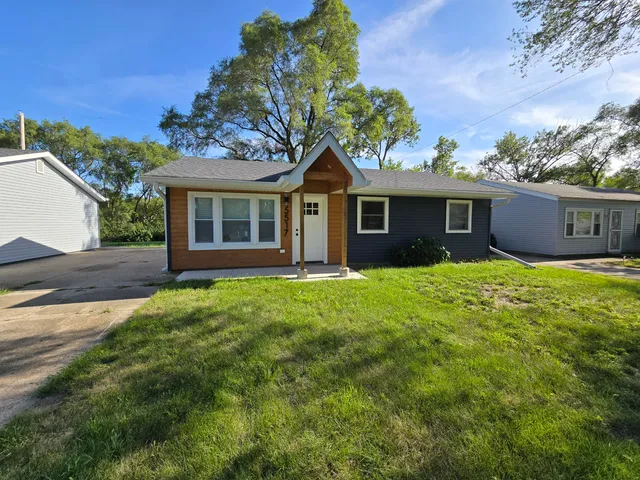 a view of house with a yard and potted plants