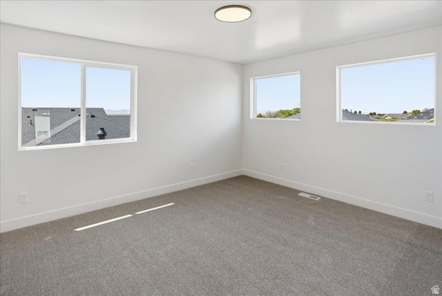 1315 West 3200 South, Unit 17 Perry, UT 84302 - Photo 47 of 58 Bright room featuring three windows, neutral carpeting, white walls, white baseboards, and a flush-mount ceiling light