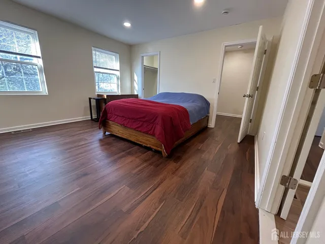 a spacious bedroom with a bed and wooden floor