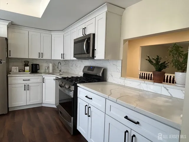 a kitchen with granite countertop white cabinets and white appliances