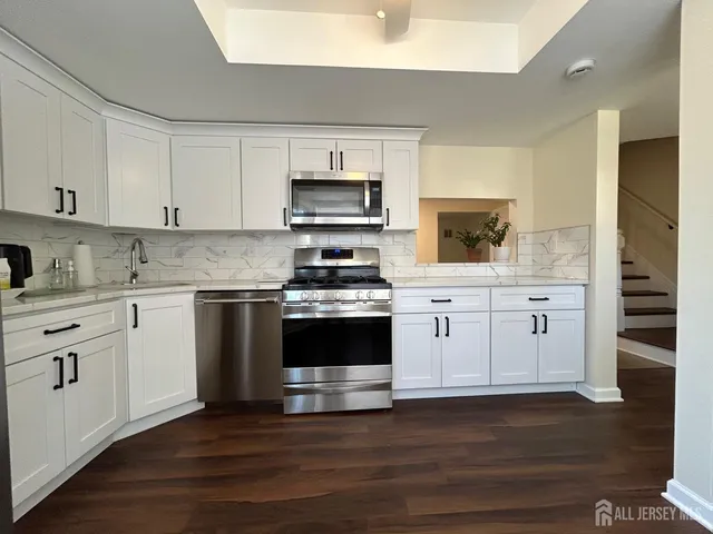 a kitchen with stainless steel appliances white cabinets and a stove top oven