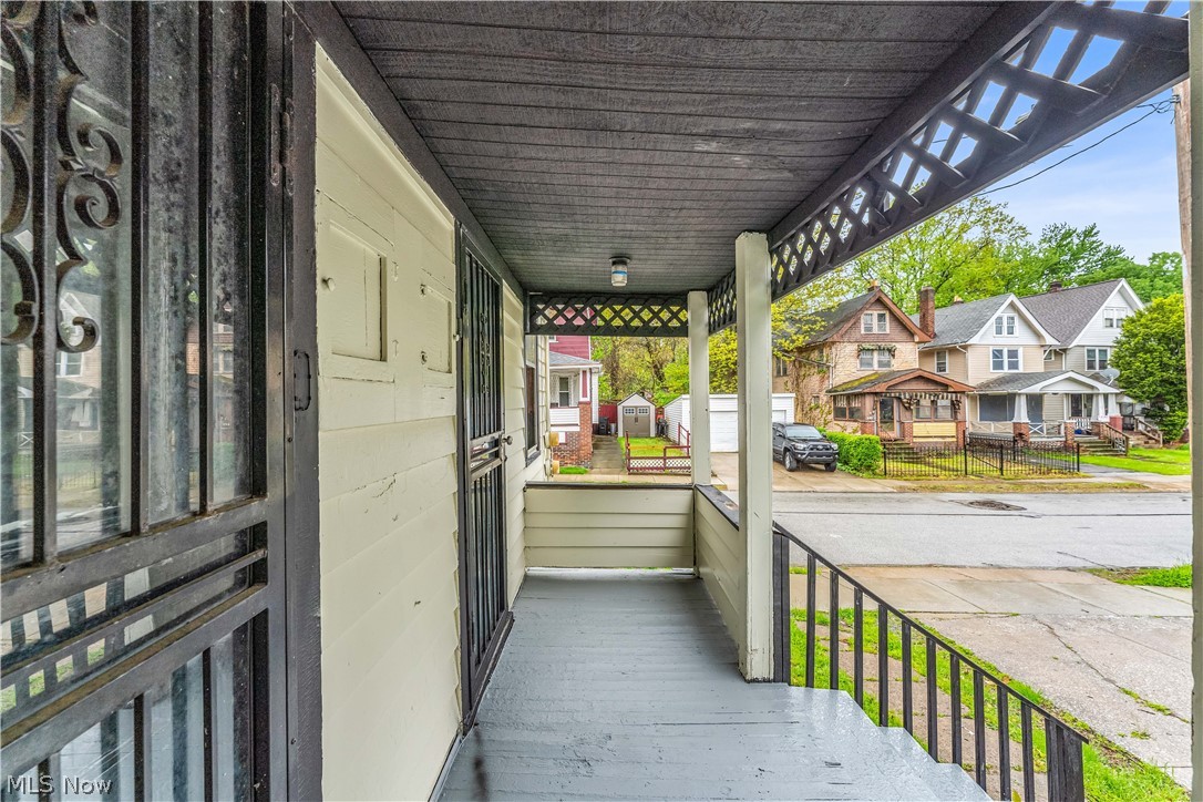 1144 East 145th Street, Unit 1/RIGHT Cleveland, OH 44110 - Photo 3 of 20 Covered front porch featuring a dark gray painted floor, white siding, black metal security doors, a lattice-patterned ceiling detail, and a flush-mount outdoor light fixture