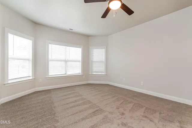 an empty room with chandelier fan and windows