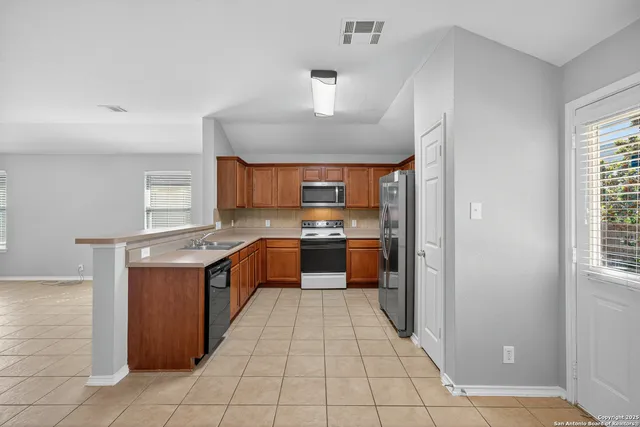 a large kitchen with stainless steel appliances a sink and cabinets