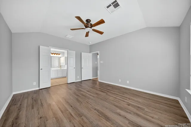 an empty room with wooden floor closet and windows