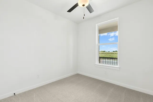 an empty room with a window and ceiling fan