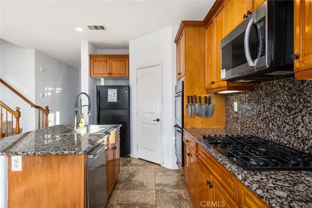 a kitchen with granite countertop wooden cabinets and stainless steel appliances