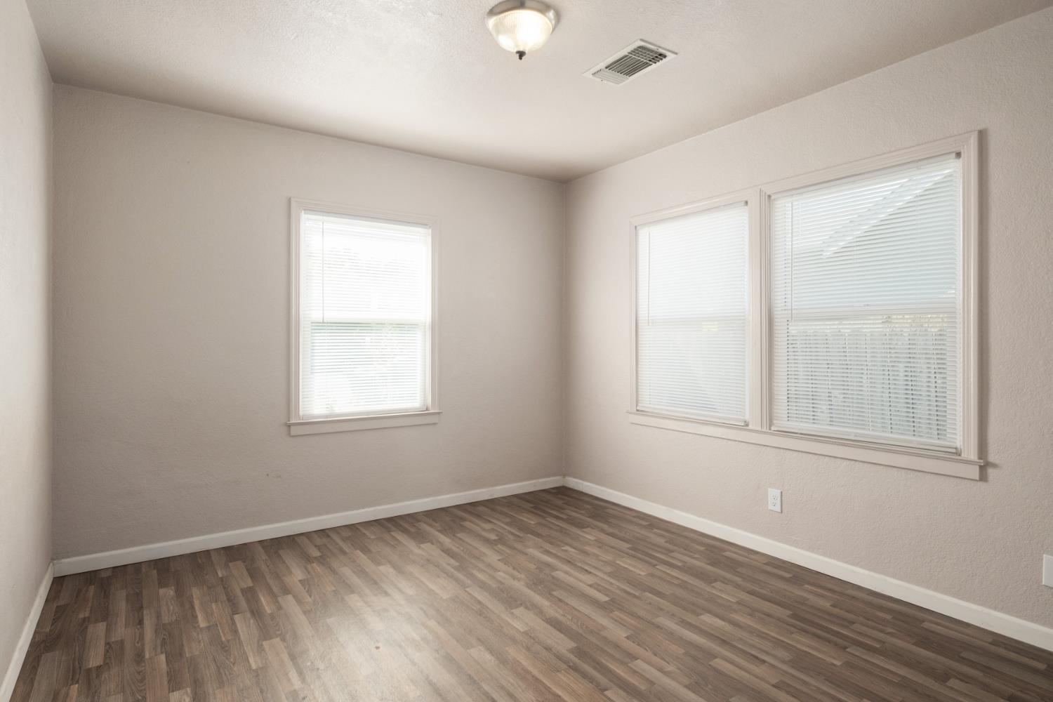 2043 11th Street Reedley, CA 93654 - Photo 13 of 21 an empty room with wooden floor and windows
