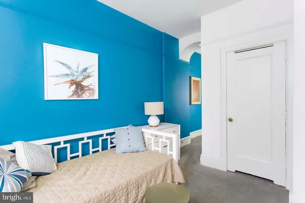 a bedroom with a bed and a lamp on dresser