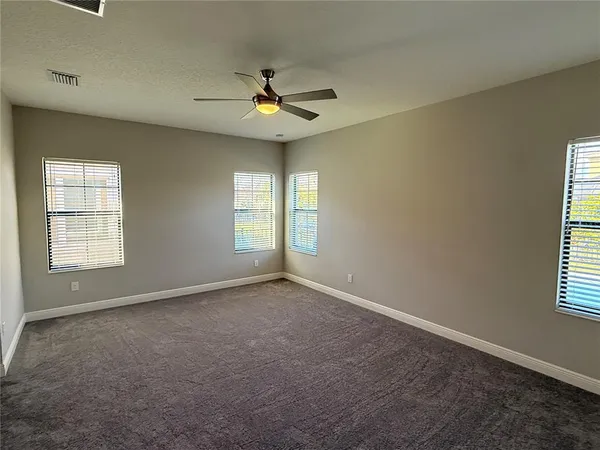 an empty room with windows and fan