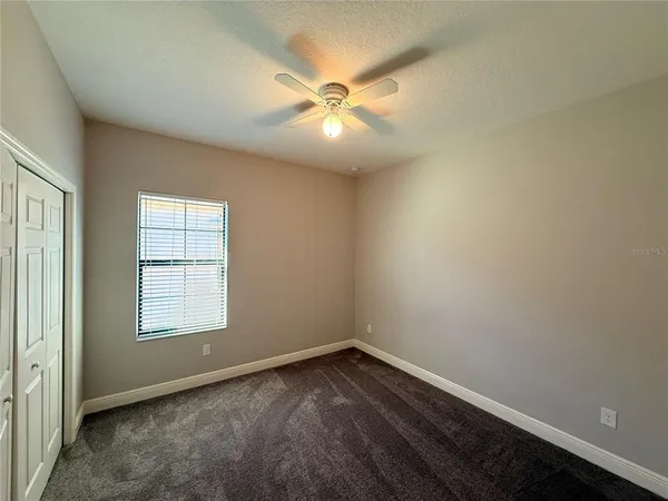 an empty room with ceiling fan and window