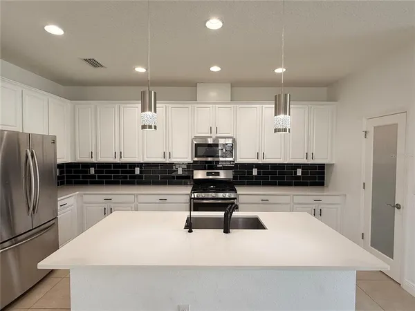 a kitchen with kitchen island white cabinets and stainless steel appliances