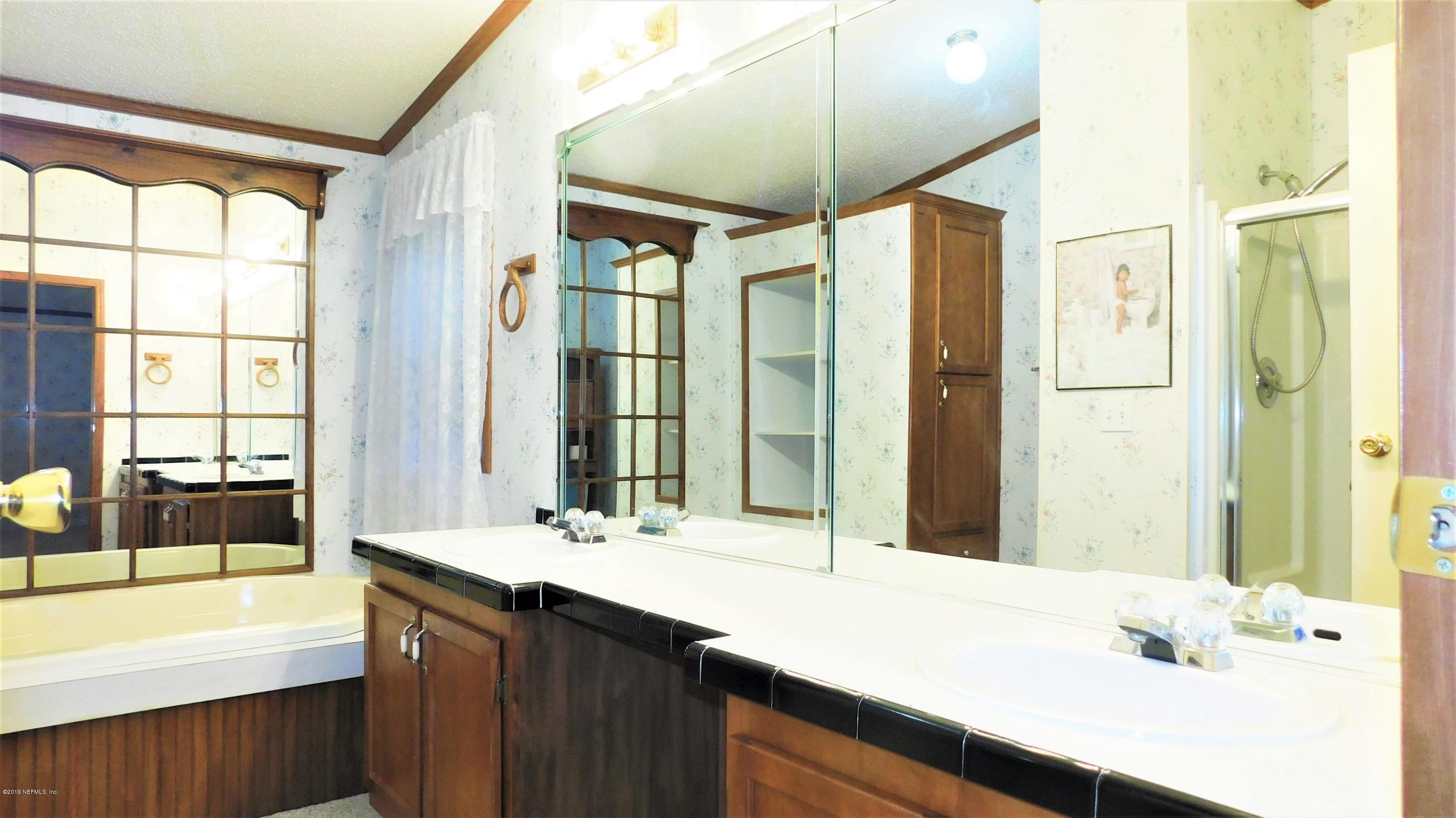 4144 Bronco Road Middleburg, FL 32068 - Photo 14 of 66 a bathroom with a double vanity sink large mirror and a bathtub
