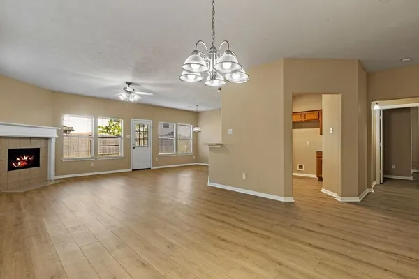 an empty room with wooden floor chandelier and windows