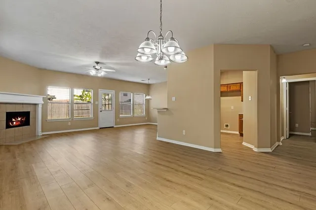 an empty room with wooden floor chandelier and windows