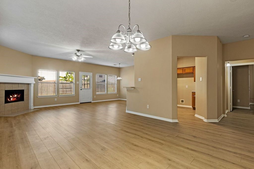32202 Anne Lane Pinehurst, TX 77362 - Photo 2 of 11 an empty room with wooden floor chandelier and windows