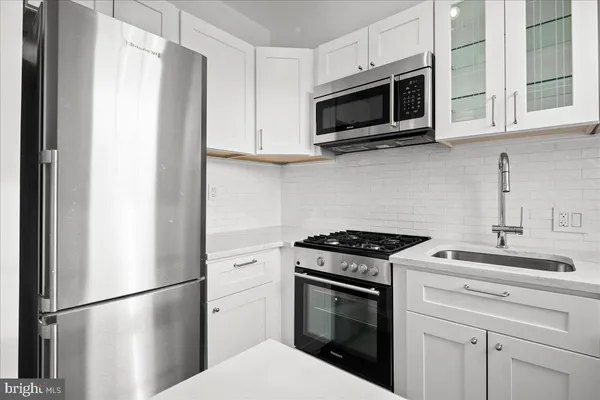 a kitchen with stainless steel appliances granite countertop white cabinets sink and a refrigerator