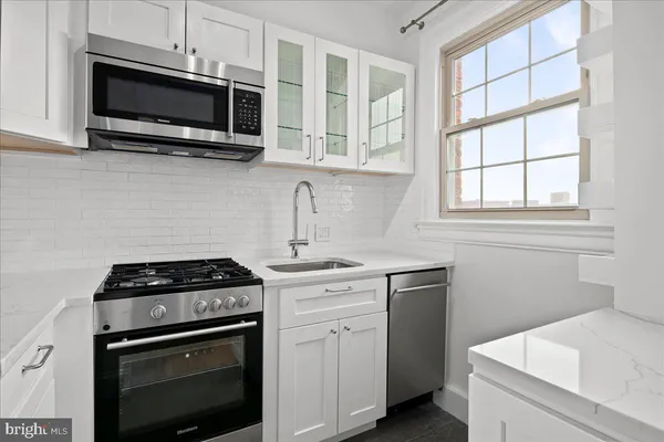 a kitchen with stainless steel appliances granite countertop white cabinets a stove top oven a sink and dishwasher