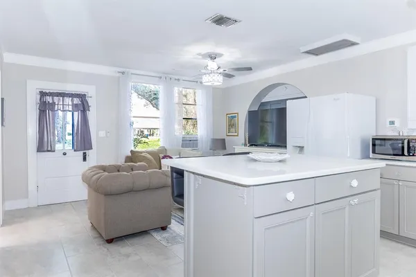 a living room with furniture kitchen view and a chandelier