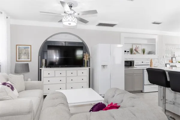 a large white kitchen with a stove a sink dishwasher and a fireplace with wooden floor