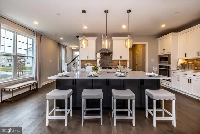 a dining room with stainless steel appliances kitchen island granite countertop a table chairs and view living room