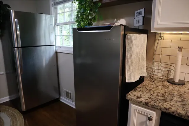 a view of a refrigerator in kitchen and an empty room
