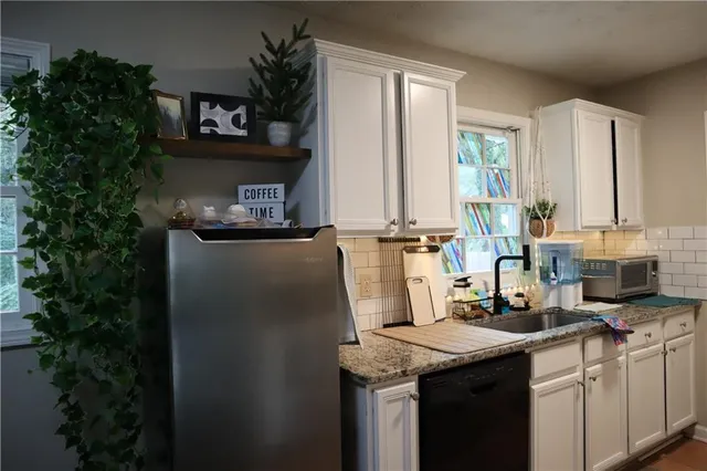 a kitchen with granite countertop a sink a counter top space and cabinets