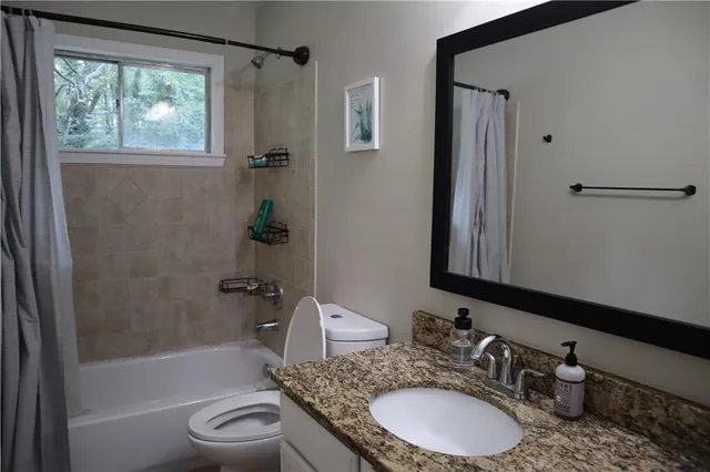 a bathroom with a granite countertop sink toilet and shower