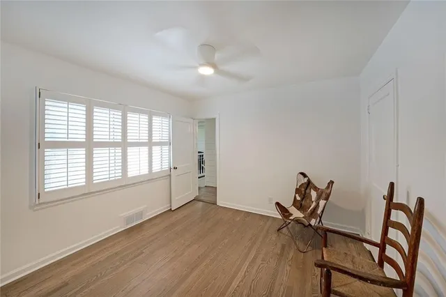 a view of a room with wooden floor a ceiling fan and windows