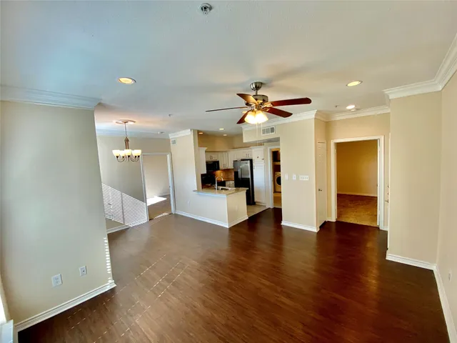 a view of an empty room and kitchen with a sink wooden floor and a window