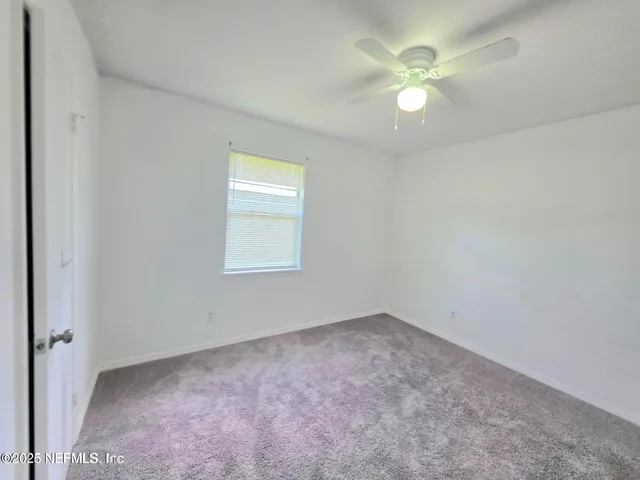 an empty room with a window and a fan