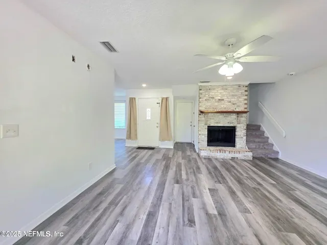 a view of empty room with fireplace and wooden floor