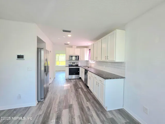 a kitchen with wooden floor and electronic appliances