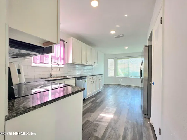 a kitchen with stainless steel appliances granite countertop a sink cabinets and wooden floor